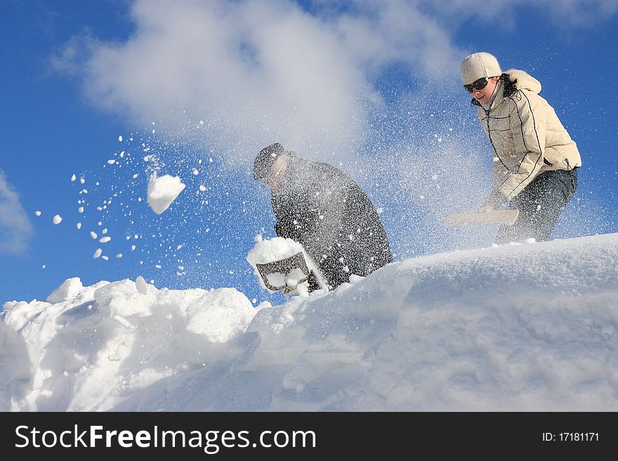 A man and young woman removing snow from a roof. A man and young woman removing snow from a roof