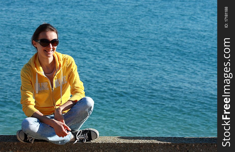 Happy young woman sitting near the sea. Happy young woman sitting near the sea