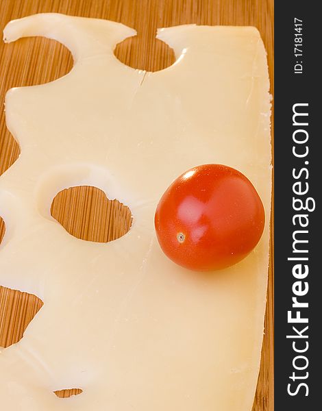 Swiss cheese slice and red tomato on a wood desk.