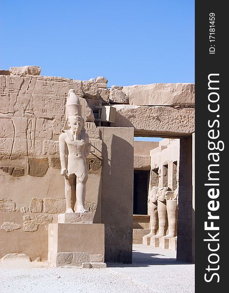 Ancient Pharaoh statue and column on backlighted sky background