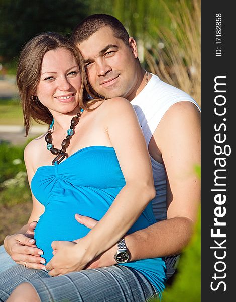 Happy husband embracing pregnant wife. Outdoors