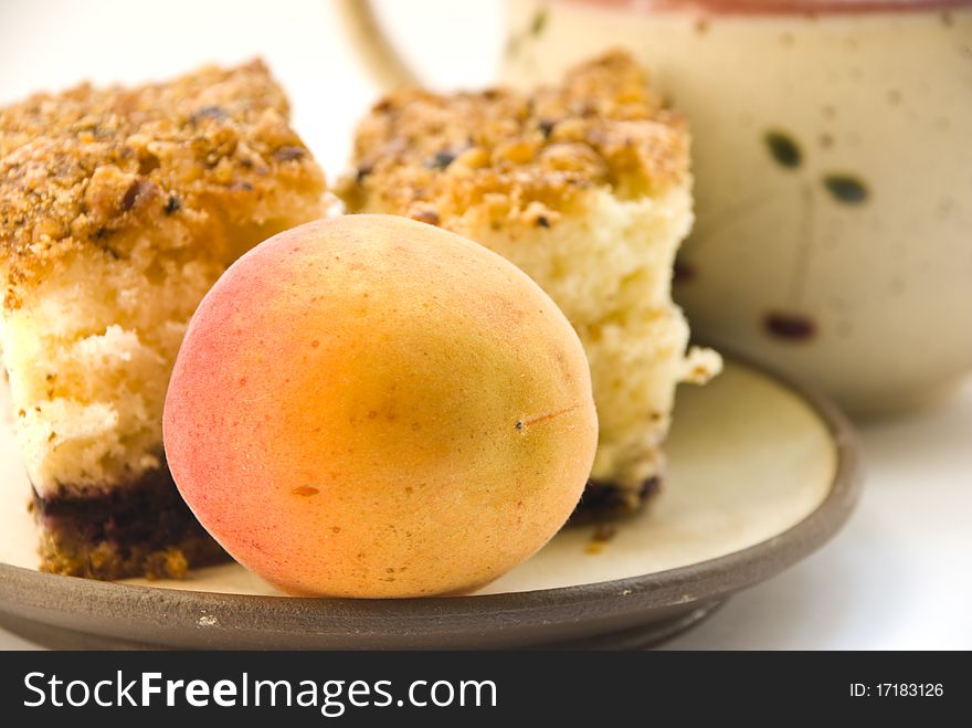 Apricot on a plate next to the cake, close-up. on a white background. Apricot on a plate next to the cake, close-up. on a white background