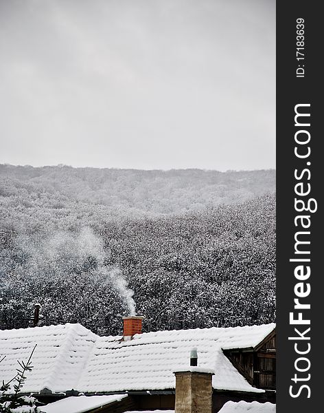 A beautiful snowy landscape whit smoking chimney in Hungary