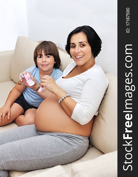 Pregnant woman and her young son sitting on sofa