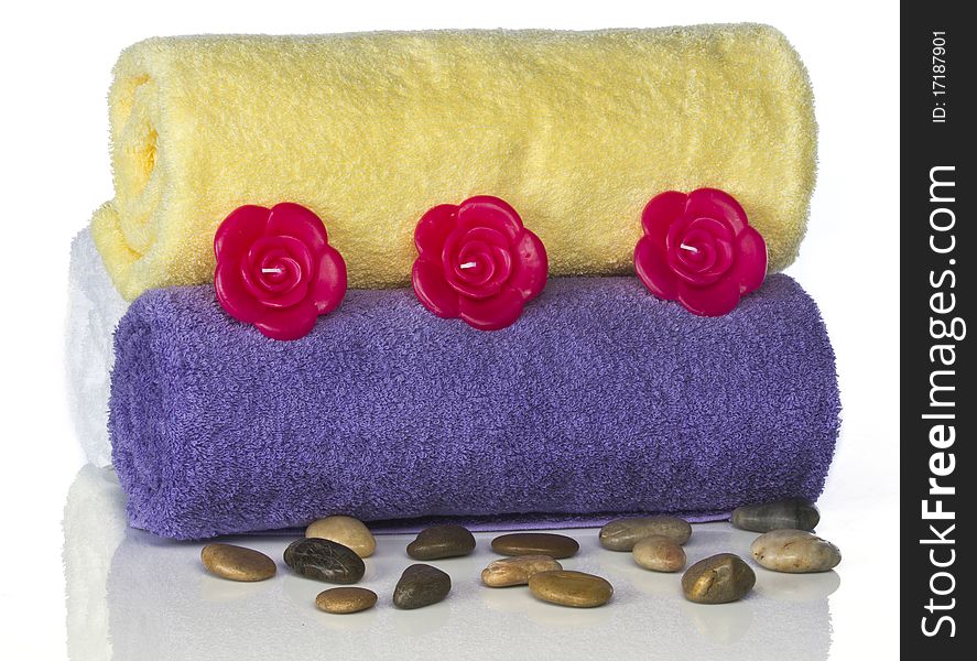 Colored towels against a white backdrop in a studio setting with candles and spa rocks. Colored towels against a white backdrop in a studio setting with candles and spa rocks