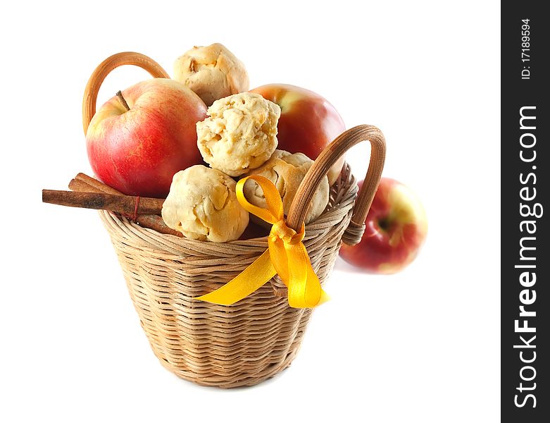 Red apples and cookies and cinnamon in a small basket. On a white background. Red apples and cookies and cinnamon in a small basket. On a white background