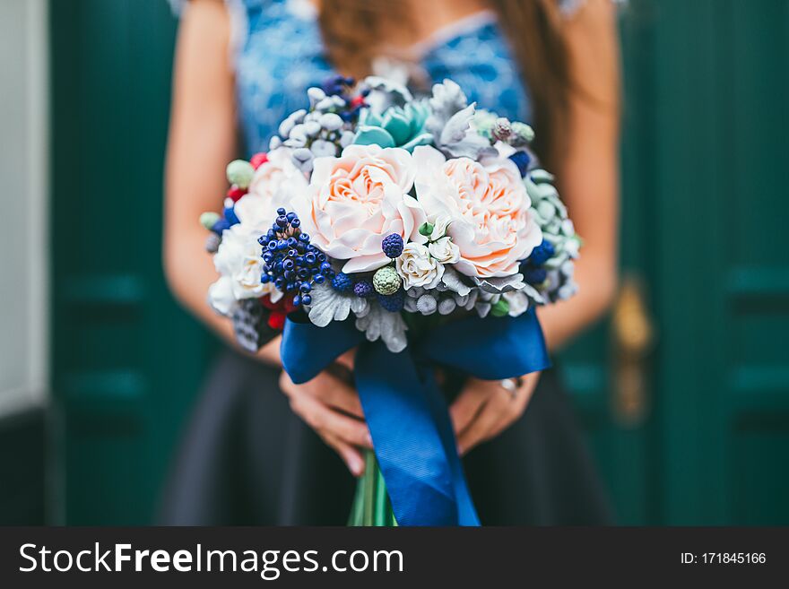 Elegant female hands holding handmade flowers made from Japanese polymer clay. They look like a real wedding bouquet