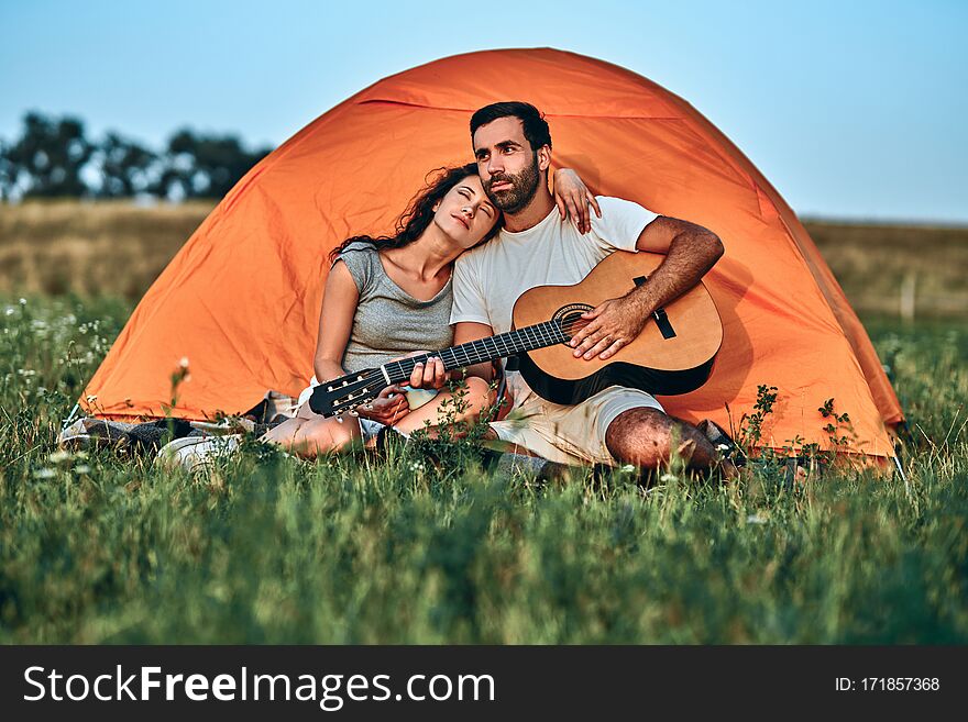 Couple in love happy relaxing nature background. Summer vacation. Boyfriend girlfriend guitar near camping tent