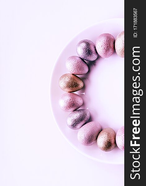 Colored painted pearl chicken and quail eggs of pink, silver, golden color on a purple plate pastel background. Minimalistic creative idea easter festive flat lay. Copyspace for text. Colored painted pearl chicken and quail eggs of pink, silver, golden color on a purple plate pastel background. Minimalistic creative idea easter festive flat lay. Copyspace for text