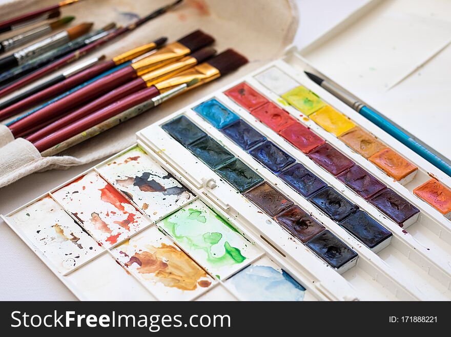 Paint brushes and watercolor paints, tempera paints on the table in a workshop, selective focus, close up