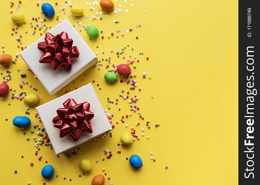 Happy birthday or party background.  Flat Lay wtih gifts, confetti and candy on yellow background. Top View.  Copy space