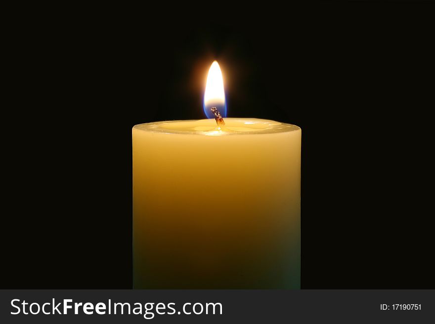 A single burning candle isolated with black background