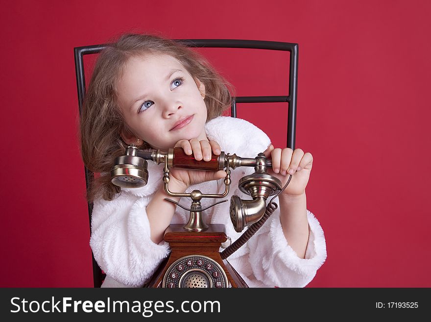 Portrait of a celebatory dressed cute dreamy little girl with an old phone. Portrait of a celebatory dressed cute dreamy little girl with an old phone