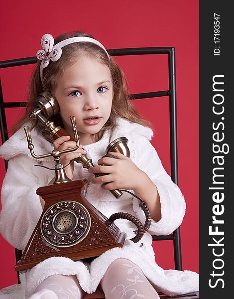 Portrait of a celebatory dressed cute  little girl talking by an old phone. Portrait of a celebatory dressed cute  little girl talking by an old phone