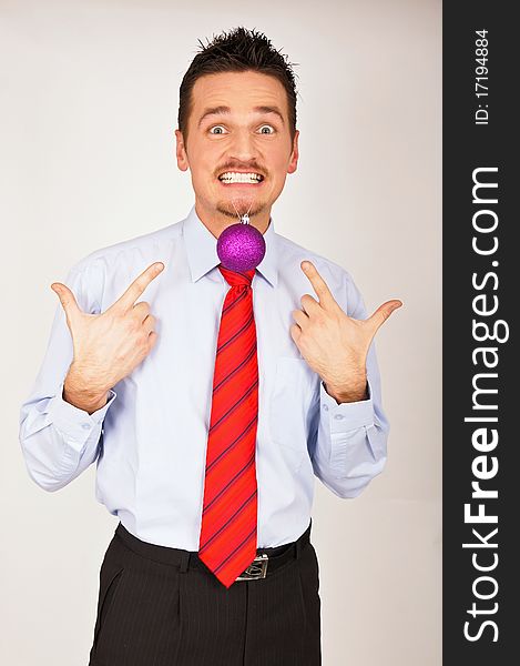 Young man in shirt and red tie has Christmas Ornament between teeth. Young man in shirt and red tie has Christmas Ornament between teeth.