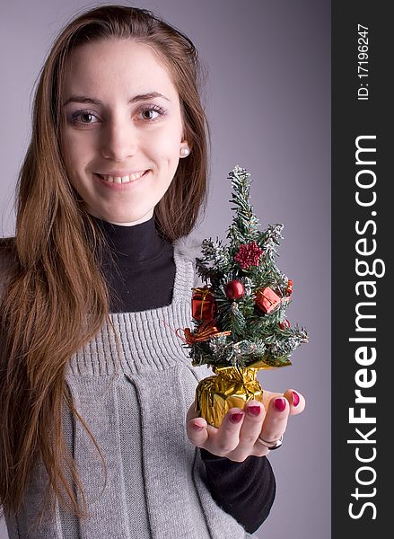 Beautiful girl smiling and holding a Christmas tree in hand