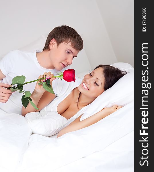 Young man kissing his beautiful girlfriend and giving her a rose (focus on the woman). Young man kissing his beautiful girlfriend and giving her a rose (focus on the woman)