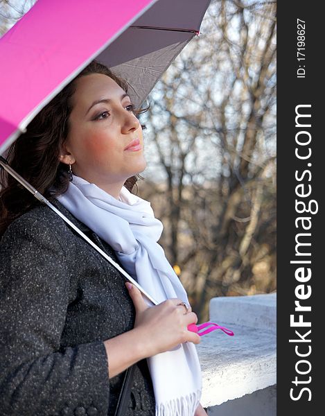 The girl leans on the parapet, holding a pink umbrella. The girl leans on the parapet, holding a pink umbrella.