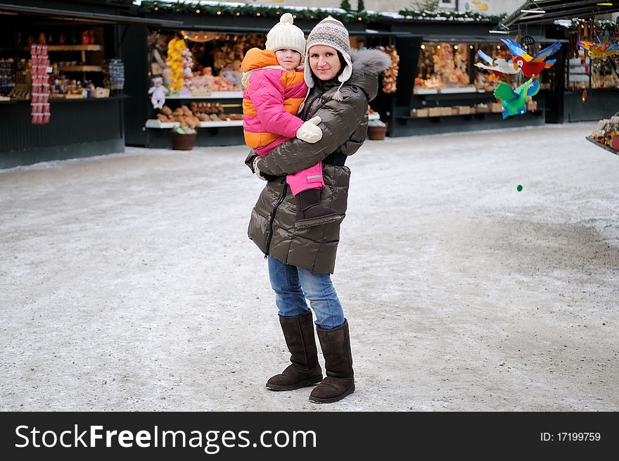 Young mother with amaze small daughter on christmas market in Europe