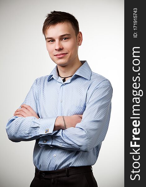 Guy with short brown hair dressed in blue shirt and black pants, posing with arms crossed on his chest. Isolated on white background. Guy with short brown hair dressed in blue shirt and black pants, posing with arms crossed on his chest. Isolated on white background