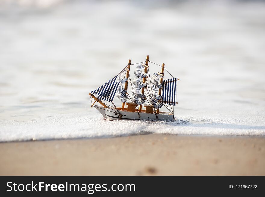 Vintage sailboat model on beach sand, discovery concept