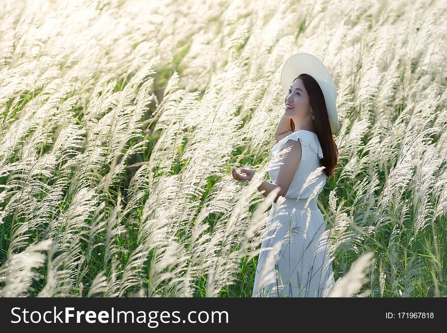 Beautiful asian woman in nature white meadow flower, her dress, and white hat standing in white grassy field, Prachuap Khiri Khan, Thailand. Beautiful asian woman in nature white meadow flower, her dress, and white hat standing in white grassy field, Prachuap Khiri Khan, Thailand