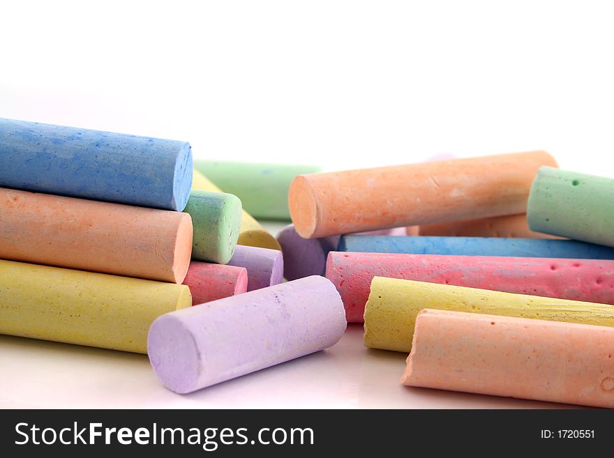 Brightly colored chalks on a white reflective background. Brightly colored chalks on a white reflective background