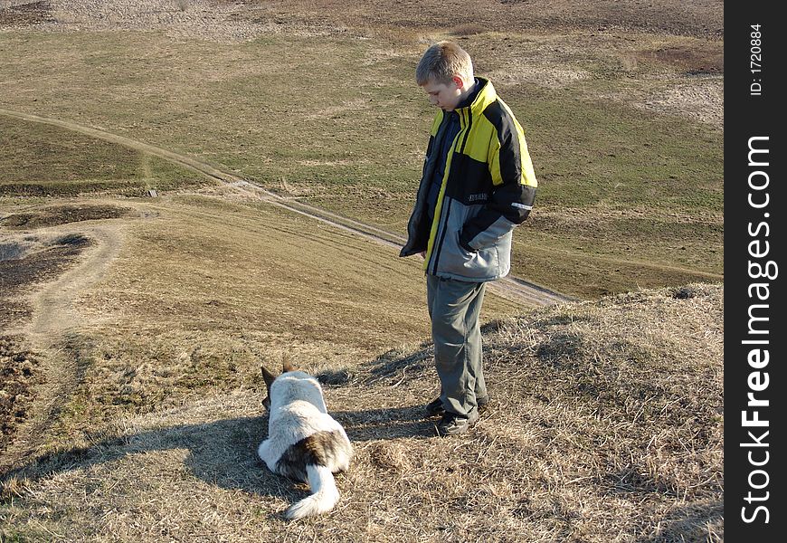 The teenager and its dog at top of a hill. The teenager and its dog at top of a hill
