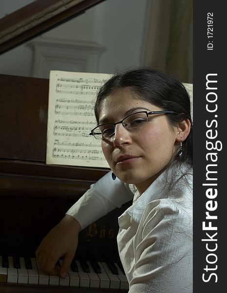 A portrait of a well-known, prize-winning female pianist, sitting at the keyboard of an open grand piano with music in the background. A portrait of a well-known, prize-winning female pianist, sitting at the keyboard of an open grand piano with music in the background.