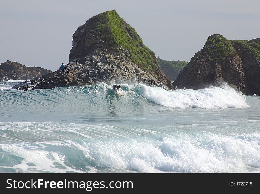 Partial view of a wave with a surfer and a small cliff in the bay of San Agustinillo in the southern state of Oaxaca in  Mexico, Latin America. Partial view of a wave with a surfer and a small cliff in the bay of San Agustinillo in the southern state of Oaxaca in  Mexico, Latin America