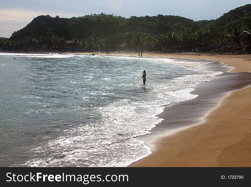 Partial view of a person and a small cliff in the bay of San Agustinillo in the southern state of Oaxaca in  Mexico, Latin America. Partial view of a person and a small cliff in the bay of San Agustinillo in the southern state of Oaxaca in  Mexico, Latin America