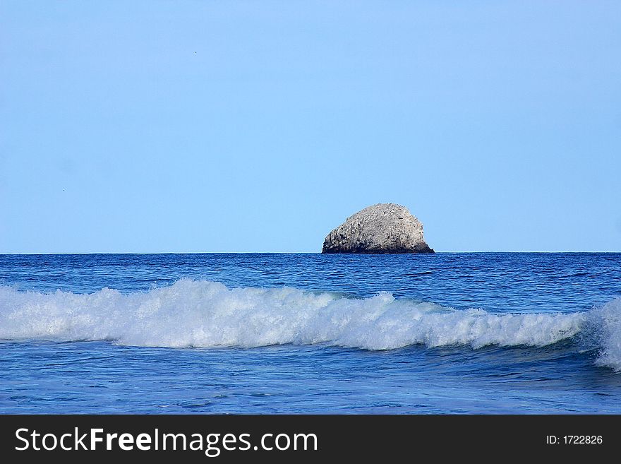 Partial view of a wave and a small island in the bay of San Agustinillo in the southern state of Oaxaca in  Mexico, Latin America. Partial view of a wave and a small island in the bay of San Agustinillo in the southern state of Oaxaca in  Mexico, Latin America