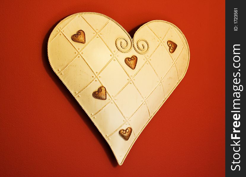 Tin heart with smaller gold hearts hanging on a dark red wall