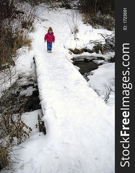 Little girl crossing foot bridge over snow and water. Little girl crossing foot bridge over snow and water