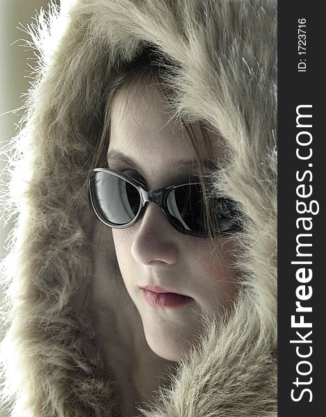 Teen girl wearing sunglasses and winter coat with fur lined hood. Teen girl wearing sunglasses and winter coat with fur lined hood