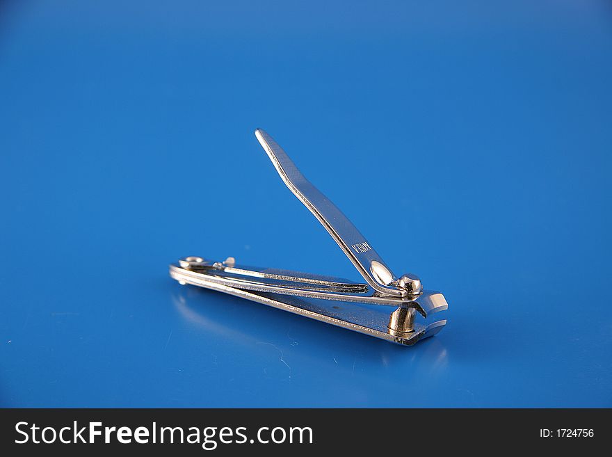 A small pair of nail clippers close up on a blue backdop. A small pair of nail clippers close up on a blue backdop.