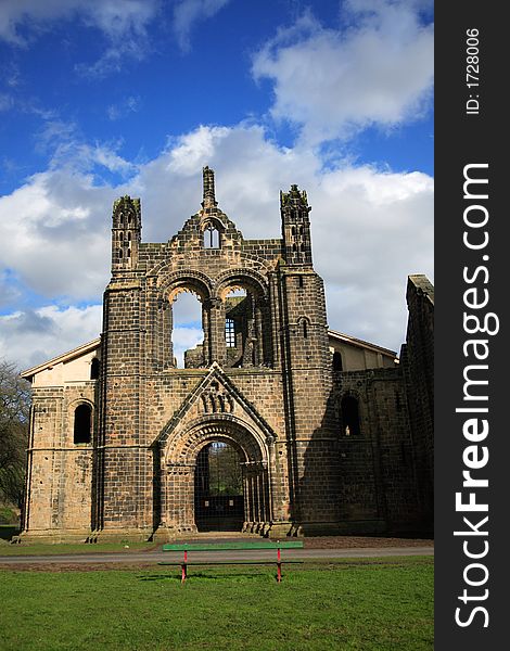 The ruins of Kirkstall Abbey against a blue sky
