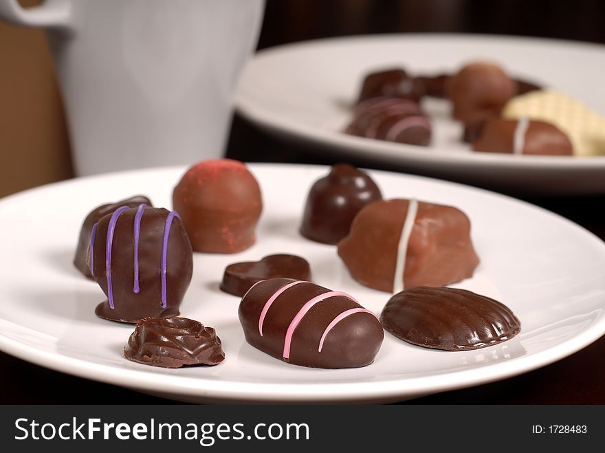 Close Up Of Two Plates Of Chocolates With A Cup Of Hot Chocolate