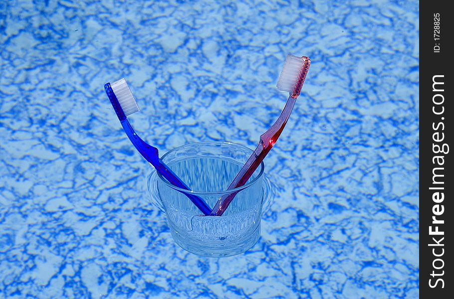 Two toothbrushes in a glass floating on water