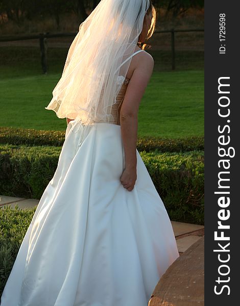 Beautiful blonde bride walking in the garden at the wedding venue. Beautiful blonde bride walking in the garden at the wedding venue.