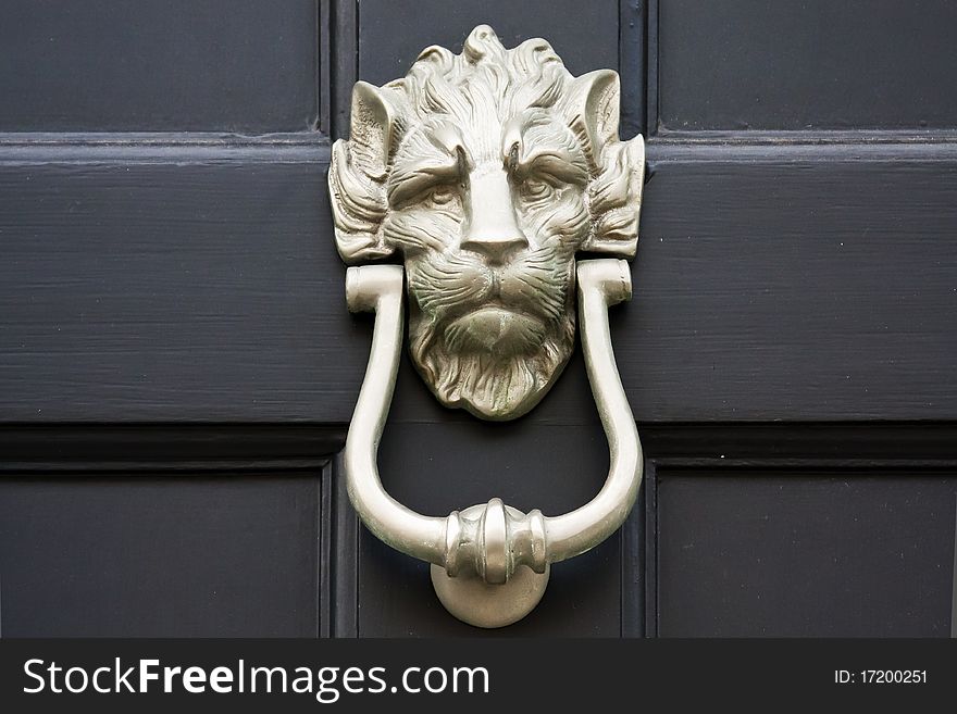 Lion shaped brass door knocker. Close up over black background. Lion shaped brass door knocker. Close up over black background