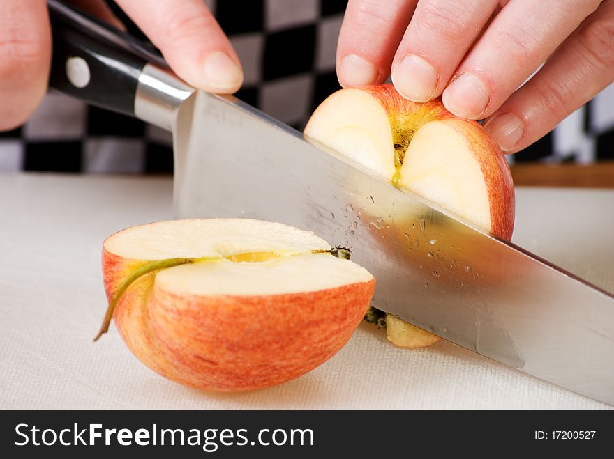 A horizontal image of a cook cutting an apple in half. A horizontal image of a cook cutting an apple in half