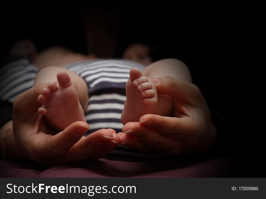 Mother holds her daughter's little feet. Mother holds her daughter's little feet