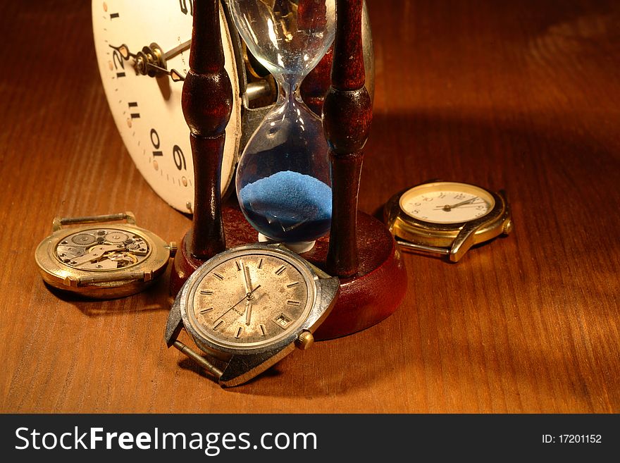 Hourglass, old watch and clock mechanism on wooden background. Hourglass, old watch and clock mechanism on wooden background