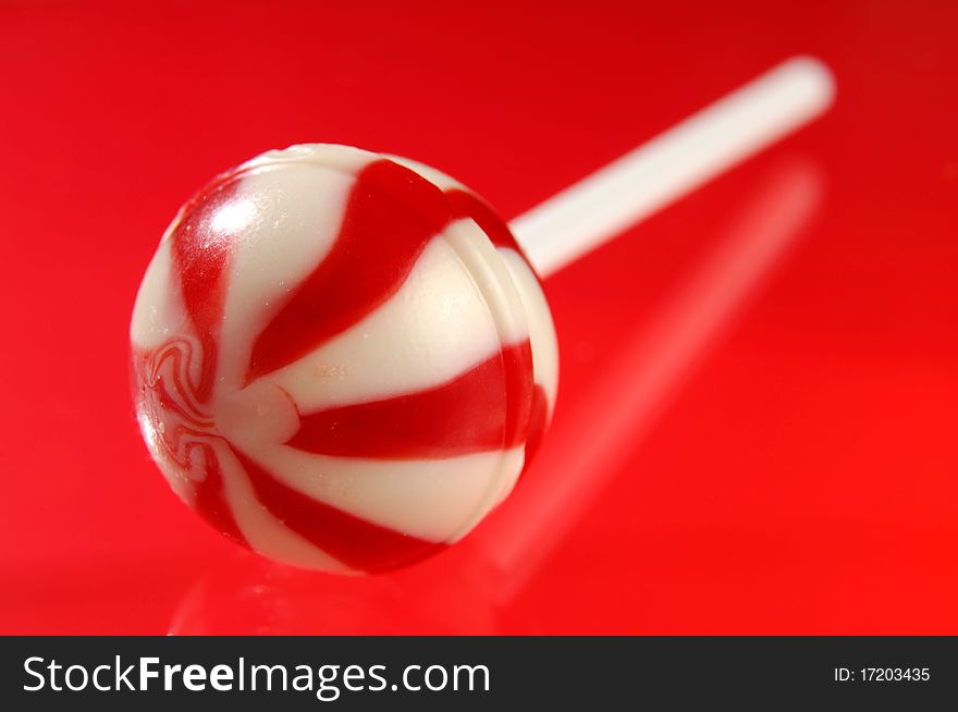 Colorful red white stripy lollipop isolated on red background