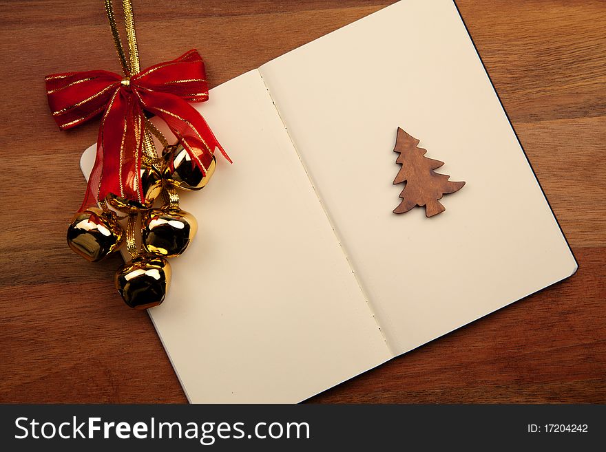 Blank Notebook With Christmas Bell And Tree On Wooden Background