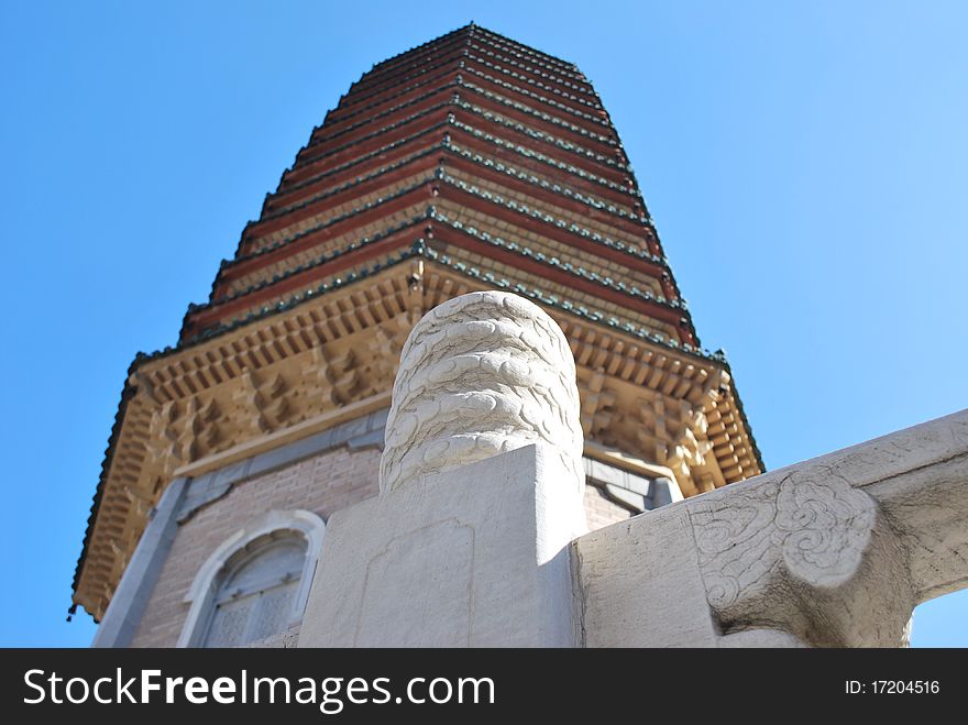 Close-up of a white stone handrail detail with an out of focus buddhist pagoda tower over a blue sky at Beijing, China. Shallow depth-of-field. Close-up of a white stone handrail detail with an out of focus buddhist pagoda tower over a blue sky at Beijing, China. Shallow depth-of-field