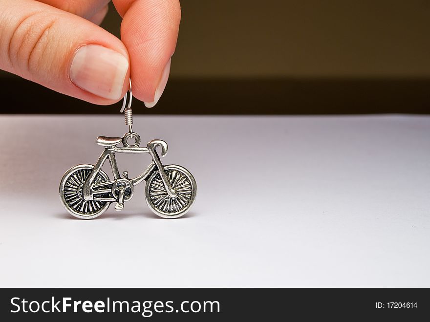 Two fingers holding a silver bicycle earring