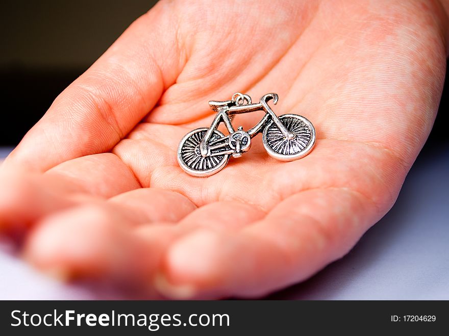 Hand holding a small silver bicycle earring