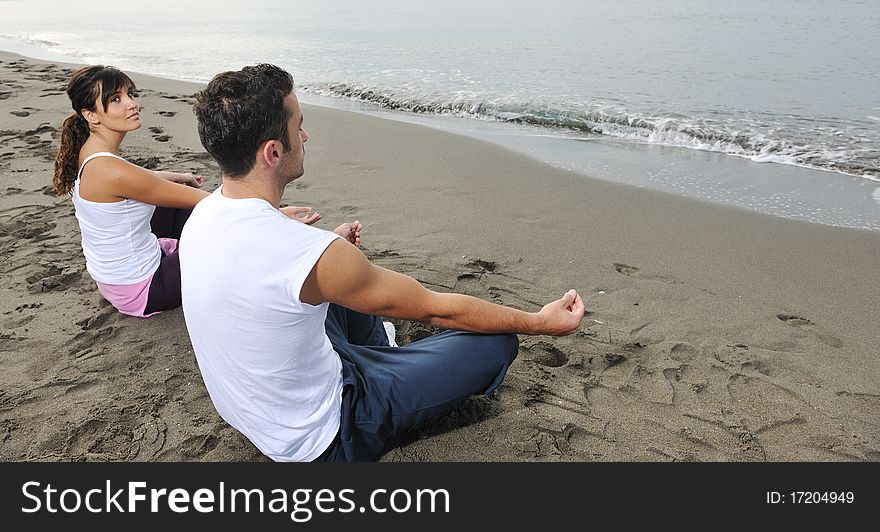 Young couple people meditating yoga in lotus position at early morning on the beach. Young couple people meditating yoga in lotus position at early morning on the beach